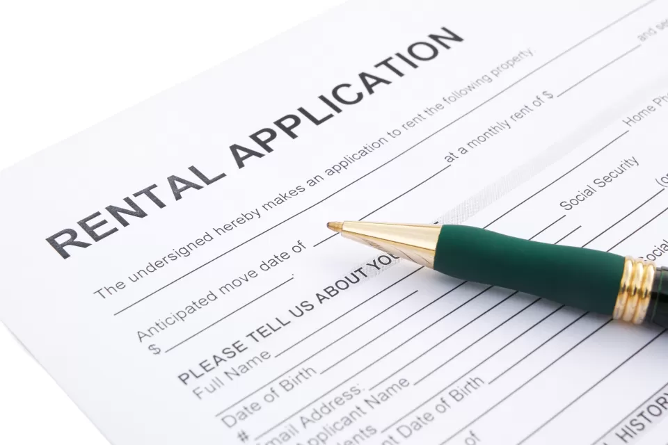 Close-up of rental application laying on table with green pen laying across the paper